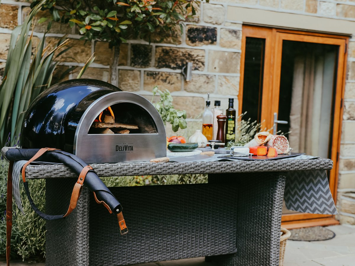 Pizza oven in black on a table with olive oils and dressings