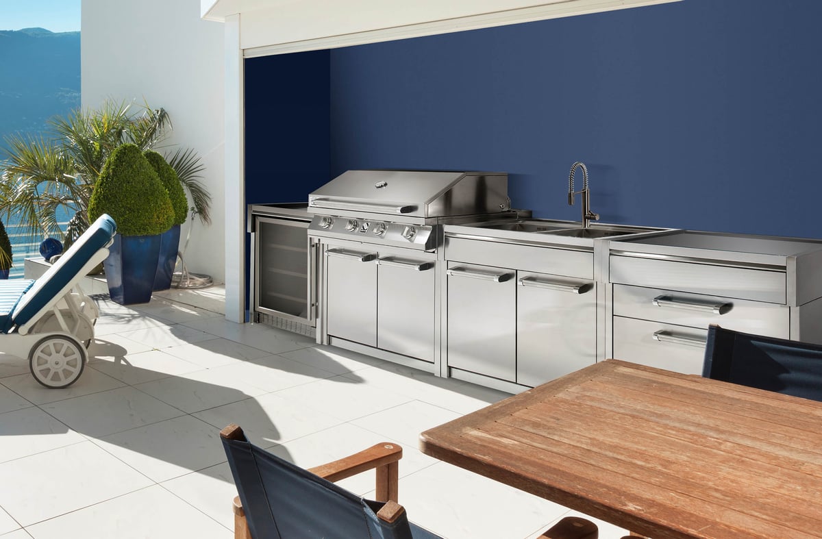 Steel outdoor kitchen in stainless steel against a dark blue wall
