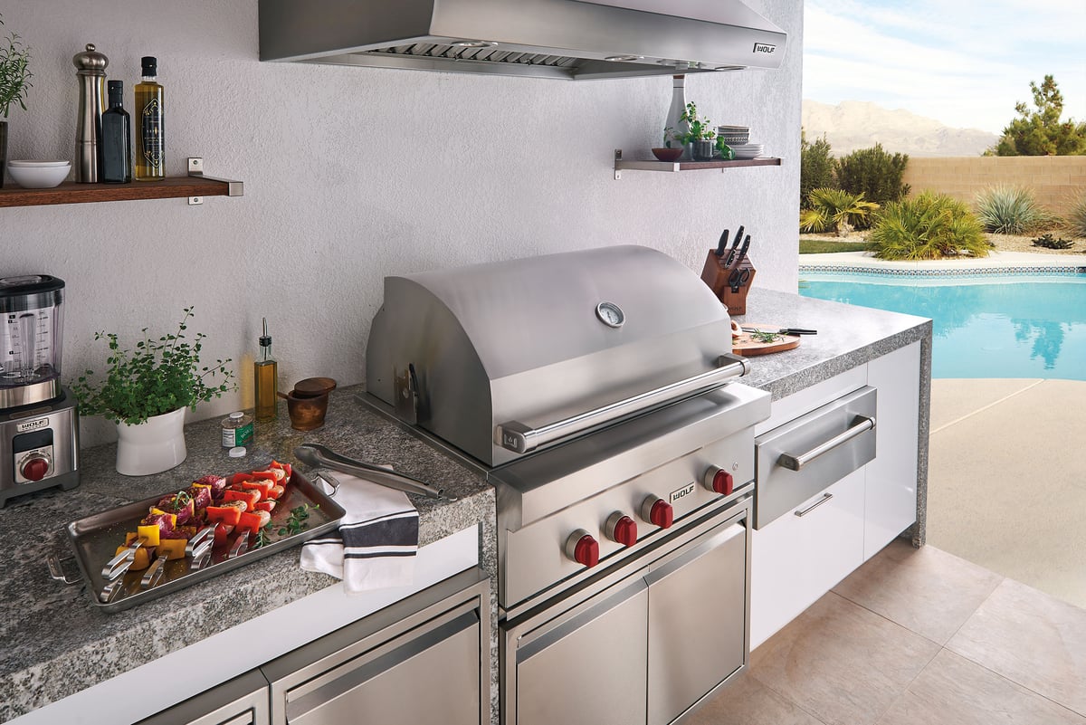 Wolf stainless steel barbecue grill with modular units and a swimming pool in he background